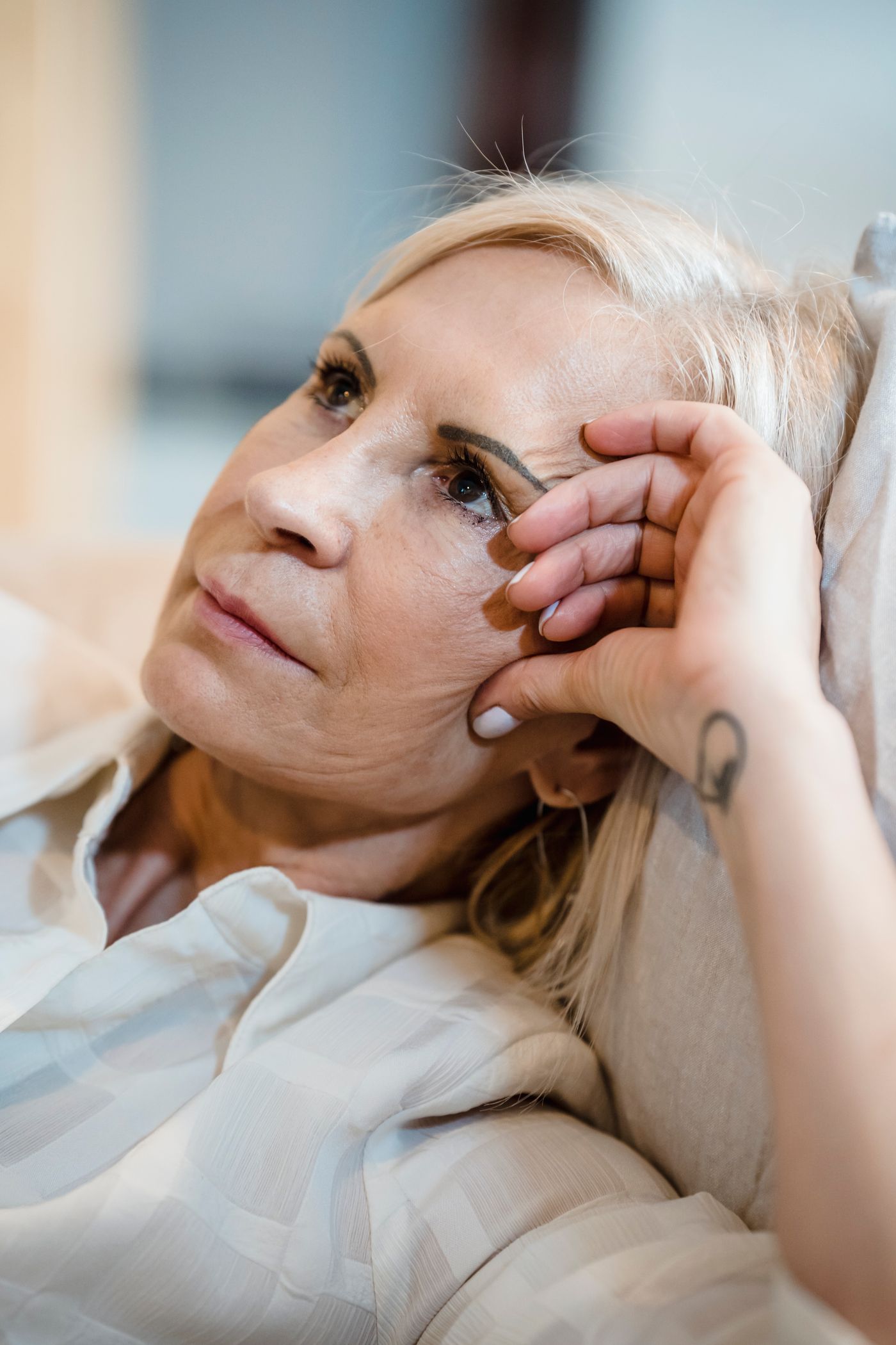 A woman resting on a sofa, looking thoughtfully into the distance